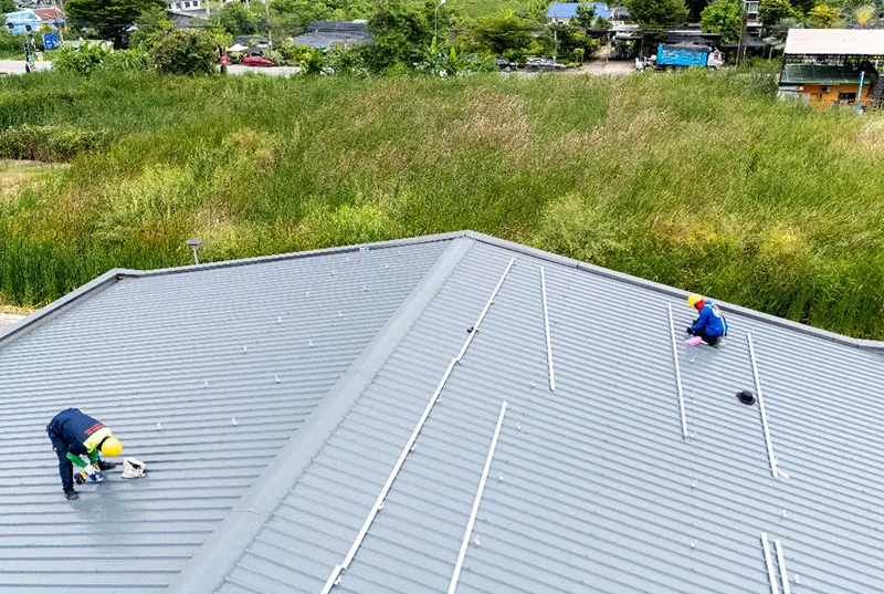 Two roofing contractors from a Central Florida roofing company working on a metal roof replacement, showcasing durable, long-lasting metal roofing solutions with a modern appeal for residential and commercial properties.