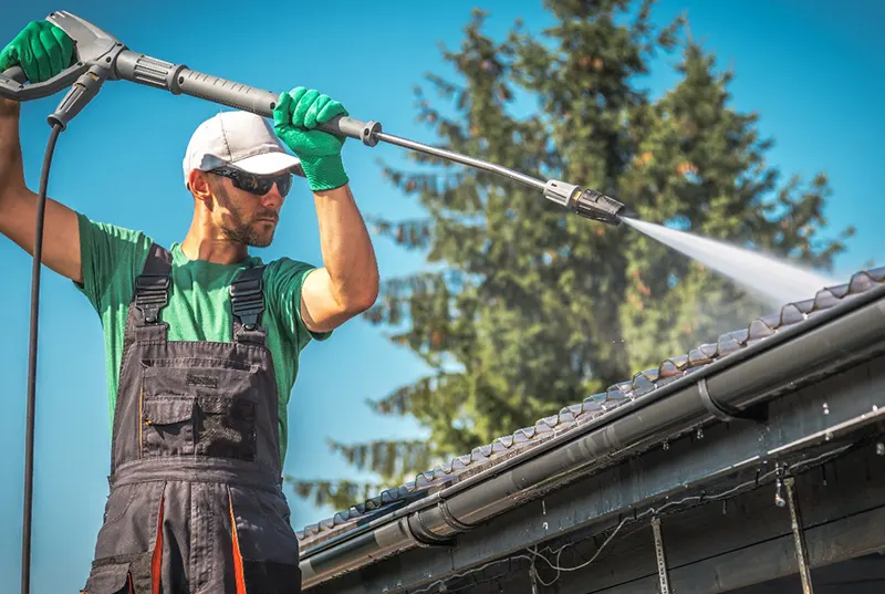 A professional roofing contractor from a Central Florida roofing company performing roof cleaning on a residential roof, ensuring long-lasting durability and maintaining the quality of residential roofing systems.