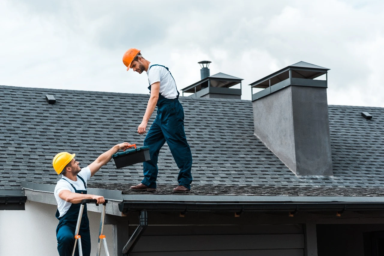 Two roofing contractors repairing a roof to meet insurance company standards in Central Florida, showcasing how a new roof can reduce insurance premiums. Highlights roof replacement, impact-resistant upgrades, and insurance discounts for durable, wind-resistant roofs.