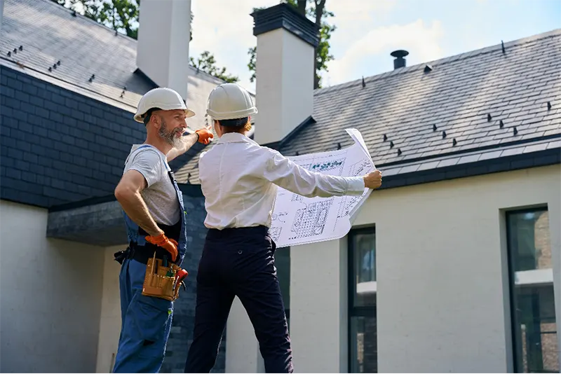 Two professionals from Sunstate Roofs, a Central Florida roofing company and roofing contractor, reviewing blueprints for a residential roofing project, showcasing expertise in both residential and commercial roofing solutions