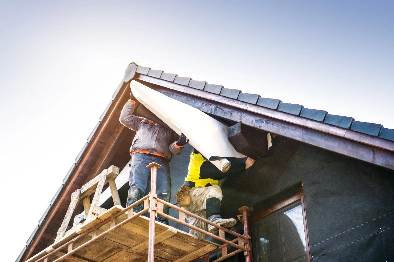 Two construction workers replacing an existing roof in Central Florida, focusing on installing materials for a durable and efficient roof replacement. Keywords: roof replacement, shingle roof, roof installation, metal roof replacement, roof repair, Central Florida.