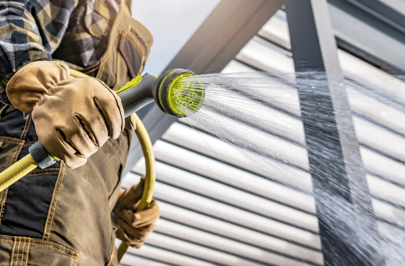 A professional cleaning technician using low-pressure water spray, a key roof cleaning tool, to safely clean residential roofs. Sunstate Roofs provides top-rated roof cleaning services and eco-friendly roof cleaning solutions in Central Florida. Search 'roof cleaning near central florida' or 'roof cleaning services near central florida' for Sunstate Roofs' trusted residential service.