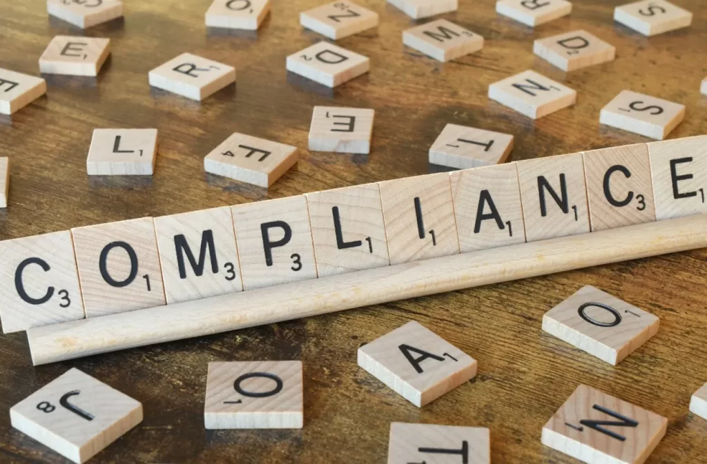 Scrabble tiles spelling 'COMPLIANCE,' emphasizing Sunstate Roofs' adherence to local building codes and regulations in Central Florida. Sunstate Roofs delivers compliant commercial roof cleaning and solutions tailored to business needs.