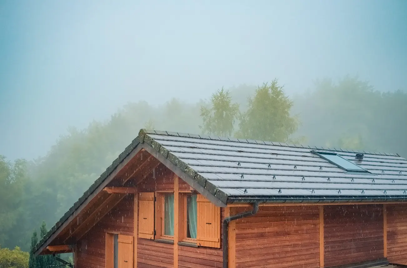 A wooden residential home with a well-maintained roof during a rainstorm, showcasing Sunstate Roofs' expert residential roof repair services in Central Florida. For 'residential roof repair near central florida' or 'residential roof repair Orlando,' Sunstate Roofs ensures wind, storm, and water resilience for your home.