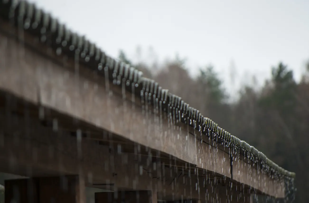 Close-up of water running off a residential roof during rainfall, highlighting Sunstate Roofs' waterproofing services in Central Florida. For reliable 'waterproofing services' or 'waterproofing services near central florida,' Sunstate Roofs ensures moisture prevention, durability, and energy efficiency for homes.