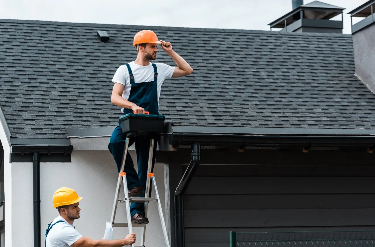 Two roofing contractors inspecting and maintaining a commercial roof, highlighting Sunstate Roofs' proactive roof cleaning and commercial services in Central Florida. Sunstate Roofs offers reliable 'roof cleaning services near central florida' to ensure long-lasting roof performance.