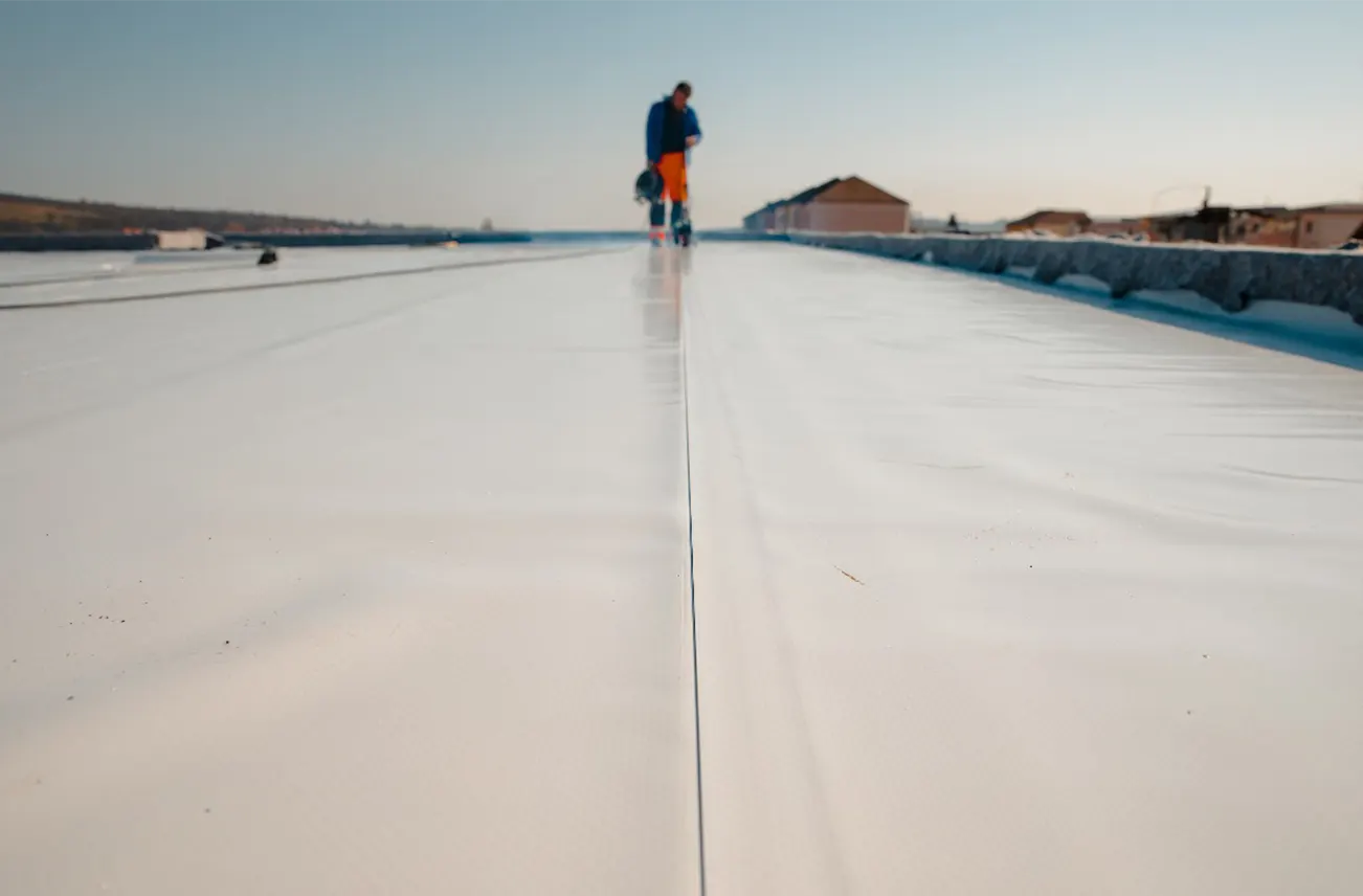 A professional roofer installing a TPO membrane on a large commercial roof in Central Florida, highlighting Sunstate Roofs' commercial services. Sunstate Roofs specializes in efficient commercial roof replacement near central florida, offering competitive commercial roof replacement costs and tax benefits for businesses.