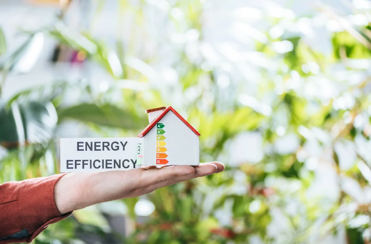 Close-up of a hand holding a model house labeled 'Energy Efficiency,' representing Sunstate Roofs' tile roof replacement process in Central Florida. Highlighting residential services, tile roof replacement pieces, and cost-efficient solutions ideal for Florida's climate.