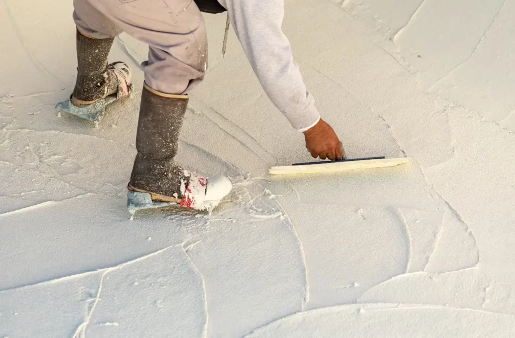 A professional applying a roof coating with specialized tools, showcasing Sunstate Roofs' commercial services in Central Florida. Sunstate Roofs provides expert roof coating application, using advanced roof coating application tools, highlighting roof coating benefits, and offering guidance on how to apply coatings effectively.