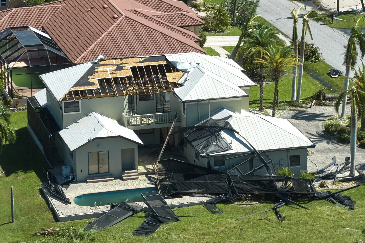 Storm-damaged home with a severely damaged roof and collapsed screen enclosure. Expert Roofing Contractor in Orlando specializes in fast, reliable roof repairs and replacements to restore homes after hurricanes and severe weather.