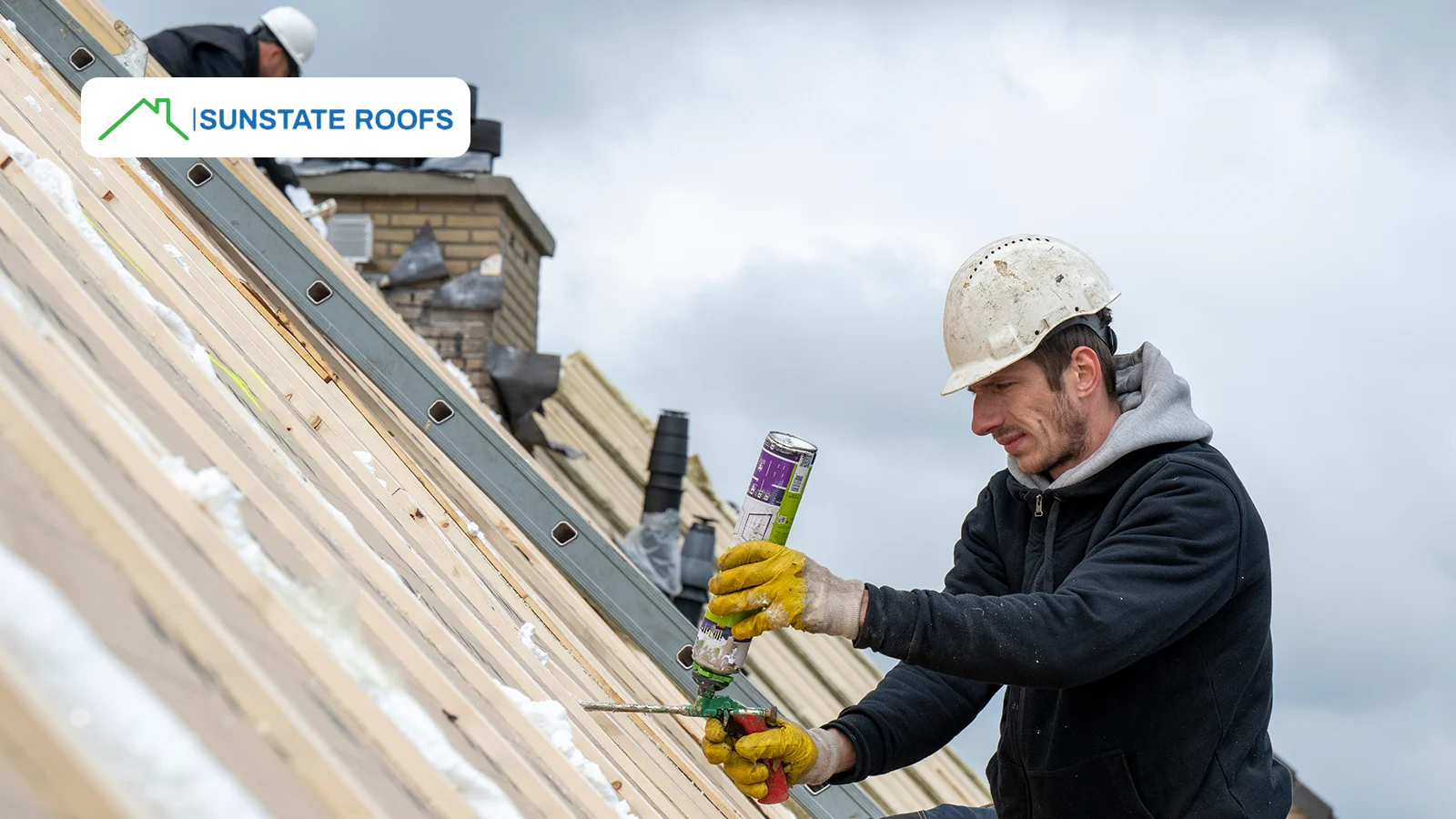 A roofing technician carefully applies sealant to a wooden rooftop under construction, ensuring enhanced waterproofing and protection against leaks, cracks, and weather-related damage. Proper residential roof maintenance helps extend the roof’s lifespan and prevent costly repairs.