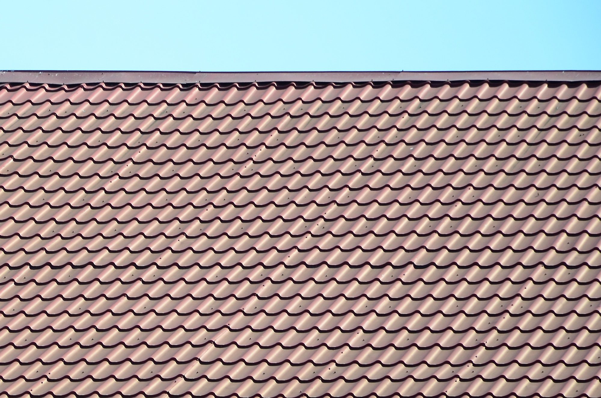 A close-up of a dark red metal tile roof, showcasing durability and premium craftsmanship. Expert Roof Replacement in Central Florida provides high-quality roofing solutions designed to enhance longevity and weather resistance.