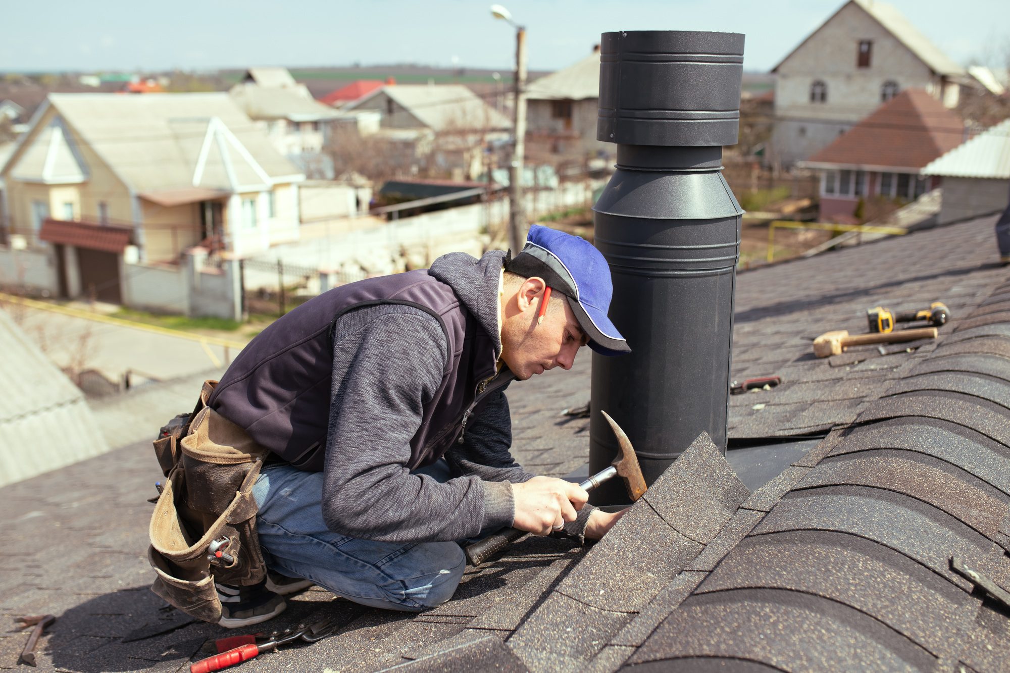 A professional master roofer in Kissimmee expertly repairs the roof with a hammer, ensuring durability and precision. 