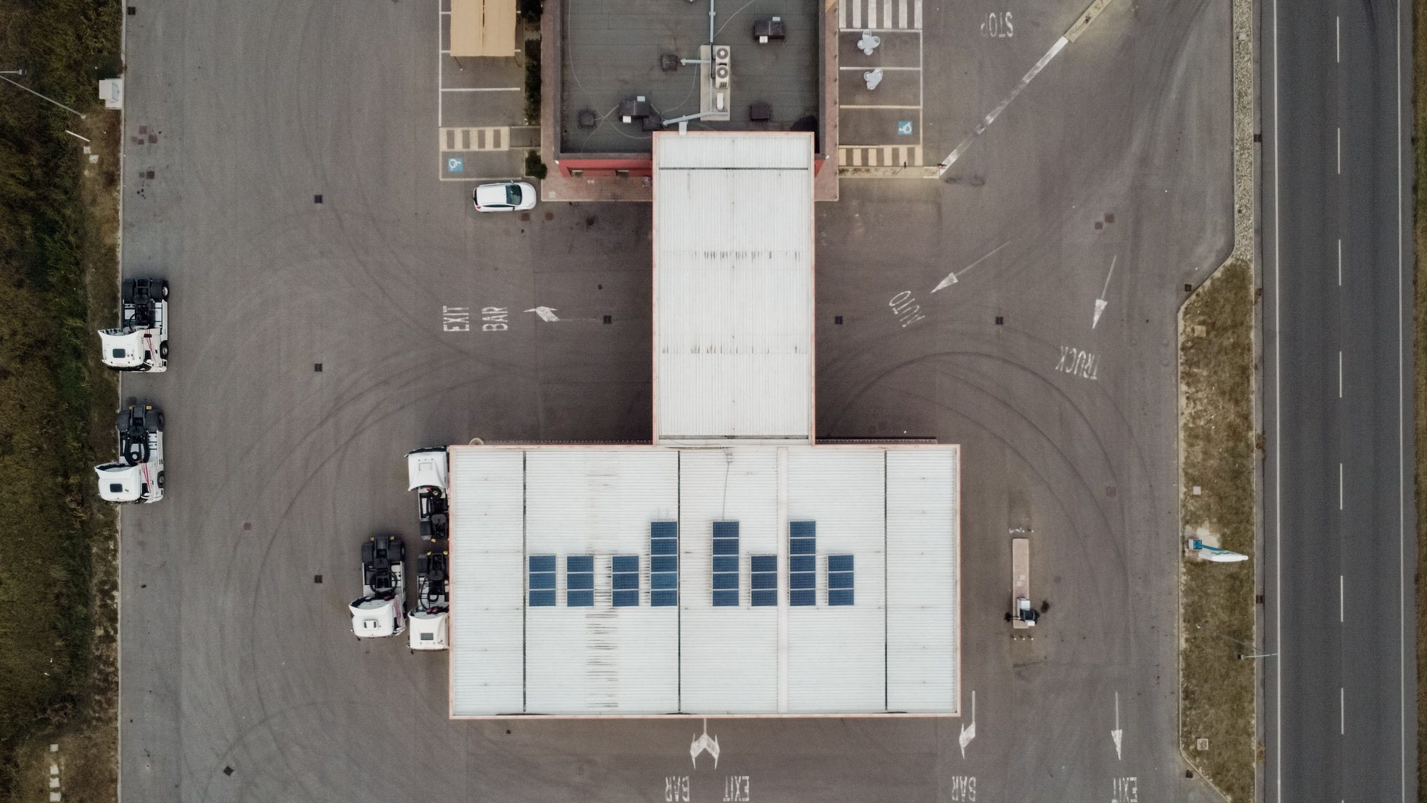 Aerial drone view of a business building with photovoltaic solar panels installed on the roof. Expert Roofing Services in Central Florida provide professional solar roofing solutions, enhancing energy efficiency and sustainability for commercial properties.