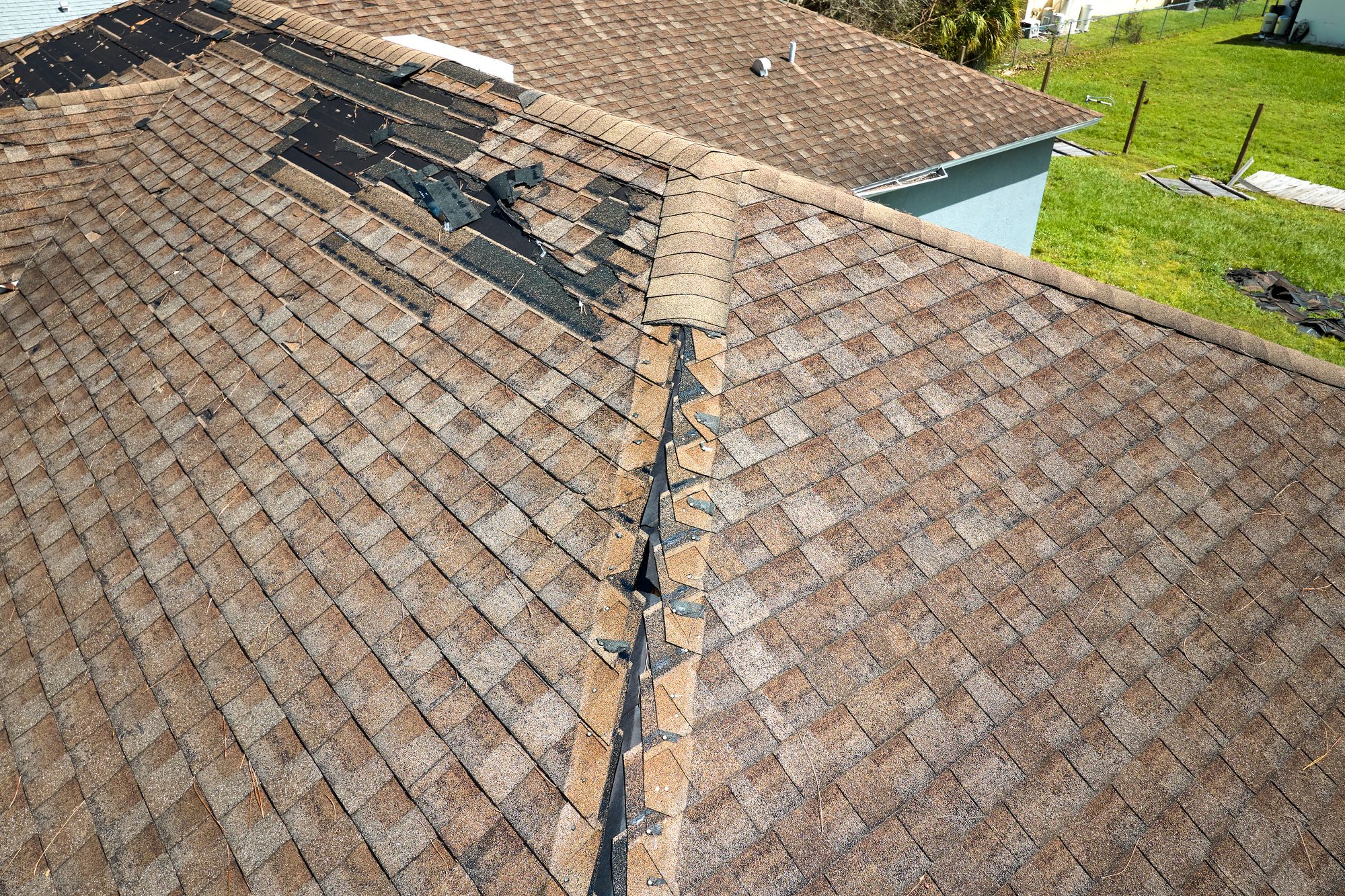 A damaged house roof with missing shingles after Hurricane Ian in Florida, highlighting the need for urgent repairs. Acorn Finance Solutions offers flexible financing options to help homeowners restore and protect their roofs after severe storm damage.