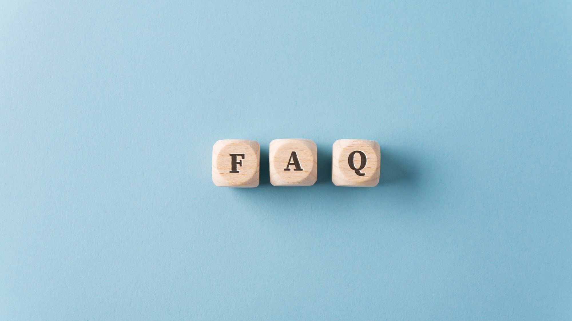 Wooden blocks spelling "FAQ" on a light blue background. Find answers to common roofing questions with Sunstate Roofs, the trusted Roofing Company in Maitland, providing expert solutions for homes and businesses.