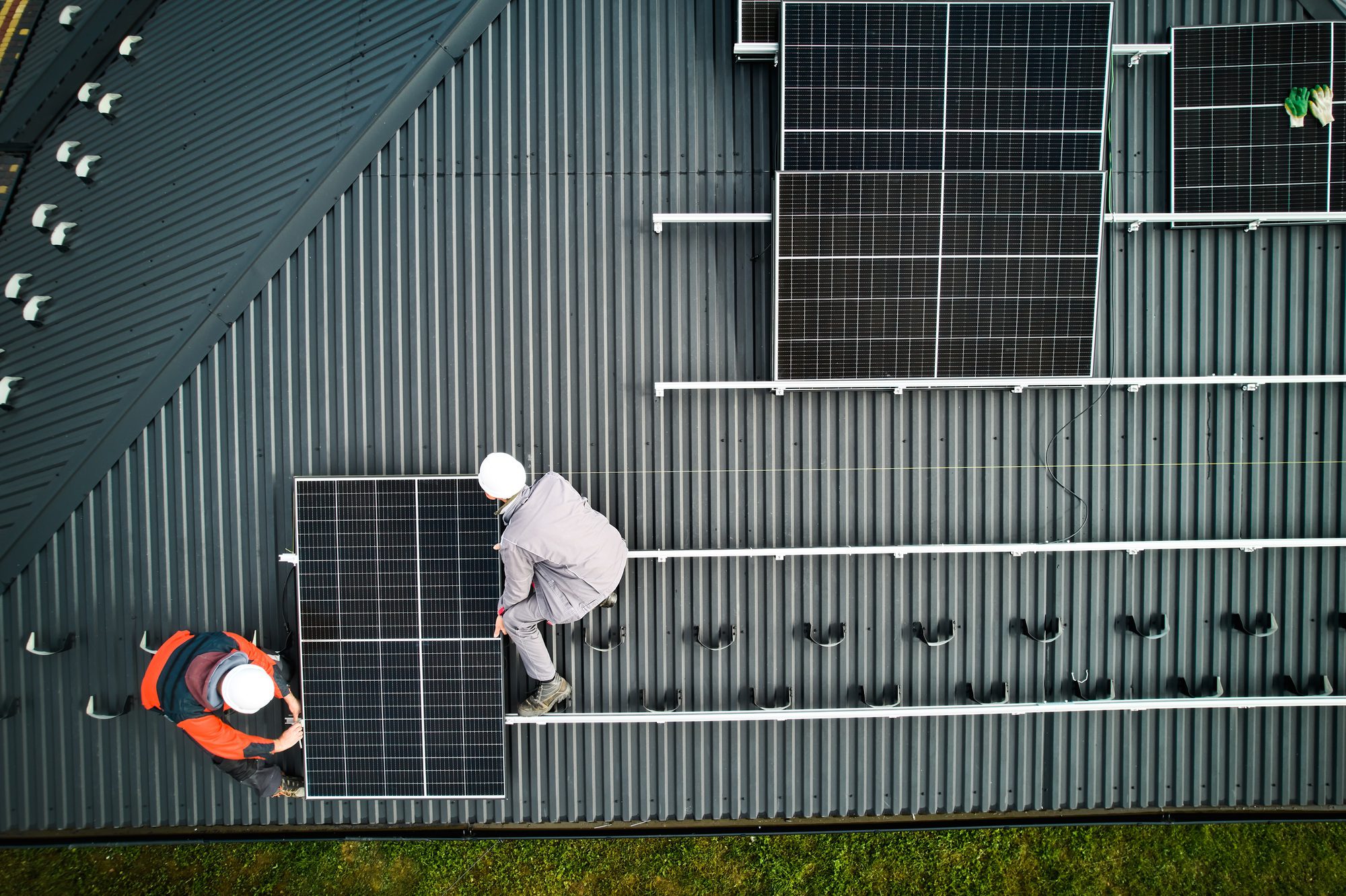 Men workers installing solar panels on a roof in Longwood, enhancing energy efficiency with expert roofing services.