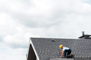 Roofing Company in Winter Park | Repairman in Helmet Fixing Roof with Hammer – Sun State Roofers