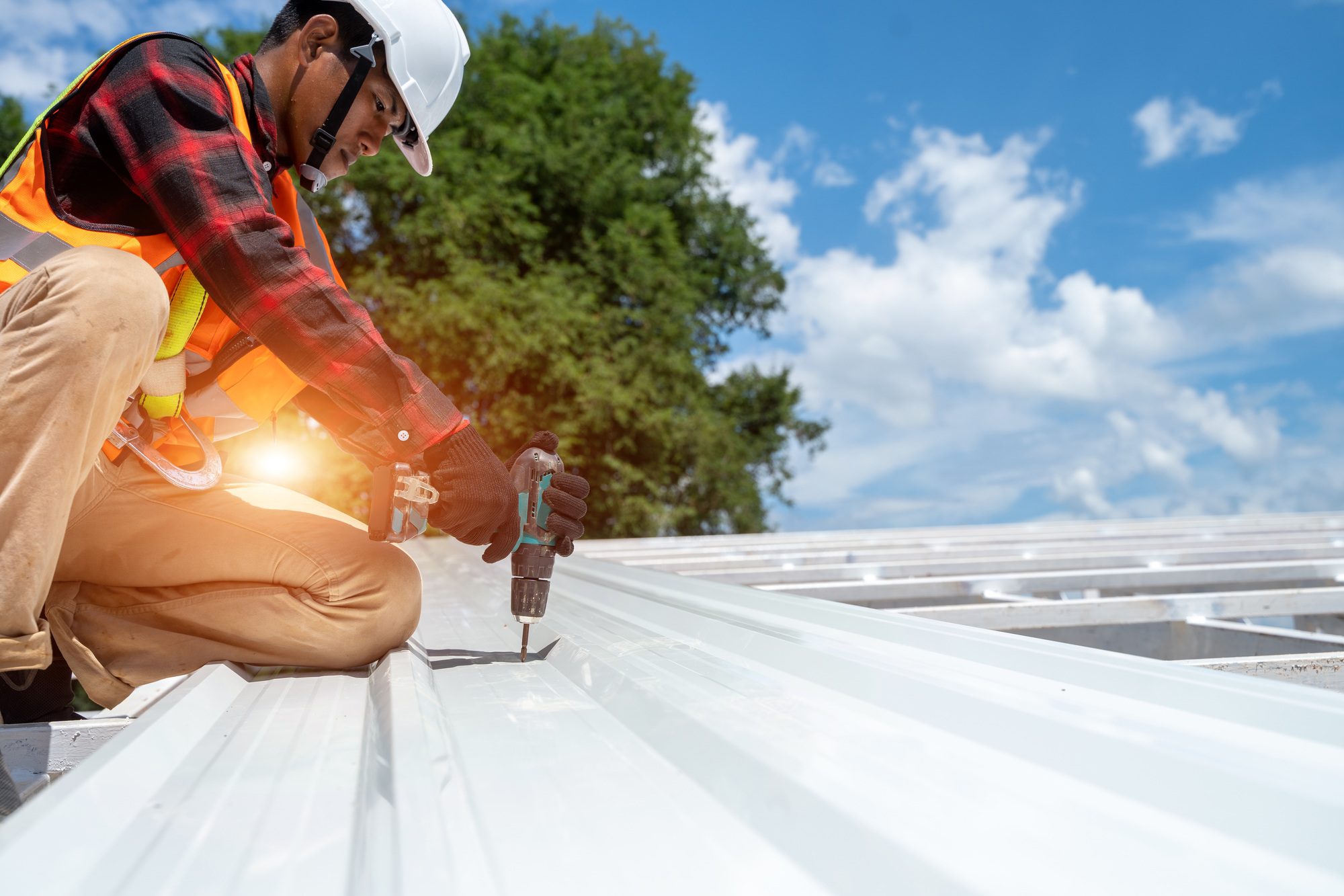 A professional roofer installing a metal profile roof using an electric drill and specialized roofing tools. Roofing Services in Central Florida provide expert metal roof installation and maintenance for durable, weather-resistant solutions.