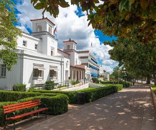 A picturesque street view in Winter Park, FL, featuring historic white buildings, lush greenery, and a peaceful walkway. Sunstate Roofs, a trusted Central Florida roofing company and contractor, specializes in residential roofing and commercial roofing solutions that complement Winter Park’s architectural charm