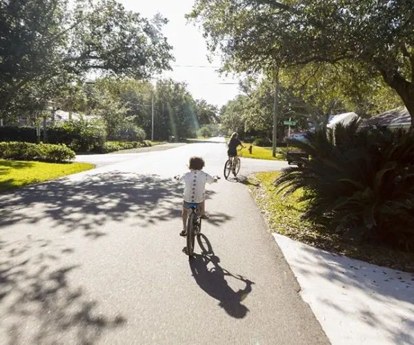 A child riding a bicycle on a tree-lined street in Winter Park, FL, showcasing the peaceful residential charm of Central Florida. Sunstate Roofs, a trusted roofing company and contractor, provides expert residential roofing and commercial roofing services tailored to the Winter Park community.